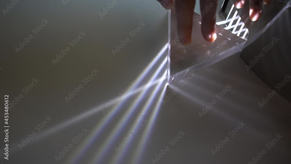 Wall mural hand turning prism showing light distortion and rainbow spectrum effect science experiment