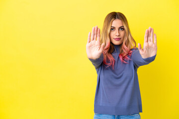 Fototapeta premium Young woman over isolated yellow background making stop gesture and disappointed