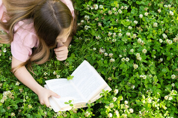 The girl studies and reads an interesting story while relaxing in the fresh air. Summer and...