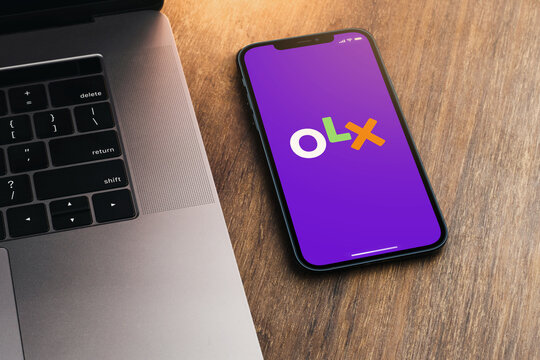 OLX app on the smartphone screen on wooden background with a computer beside it. Top view. Rio de Janeiro, RJ, Brazil. August 2021.