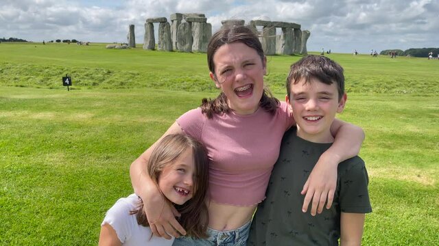 Young children posing for a photograph outside the stone circle of Stonehenge in England. Candid tourist clip