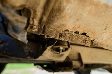 Close-up Body repair and welding work required. Rust on a gray old car. Rust hole on an old worn out painted metal surface.
