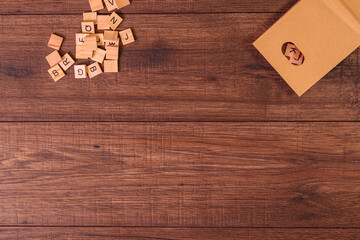 Frases motivadoras con letras de madera y una bolsa de papel con muchas fichas de letras sobre un fondo de madera de roble, cerezo, pino, de color marrón y rustico.
