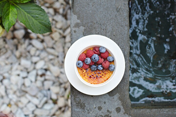 Tasty creme brûlée with heath-berry and raspberry. Creme brulee dessert with blueberries. Close up.Fresh homemade creme brûlée with burnt sugar isolated on white background. Selective focus 