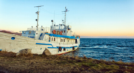 The ship is moored on the shore of Lake Baikal. Autumn landscape. The nature of Eastern Siberia. At sunset.