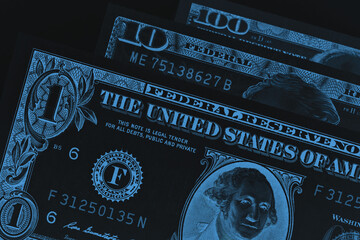US banknotes of 1, 10 and 100 dollars close up. Dark inverted photo. Black and blue business...