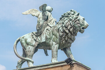 Statue of a big lion with genius of music, an angel with wings and a musical instrument at Concert...