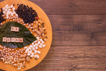 Wooden plate with seeds and legumes for vegans and vegetarians on a rustic wooden table