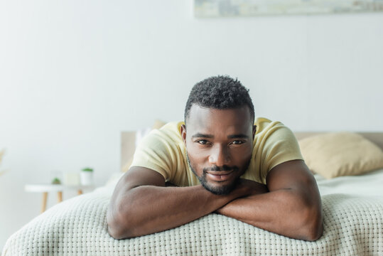 bearded african american man in t-shirt lying on bed