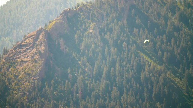 Paraglider flies around the Rocky Mountains.