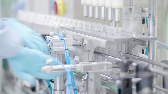 Factory worker operates bottling machinery on the production line. 