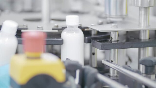 Factory worker operates bottling machinery on the production line. 