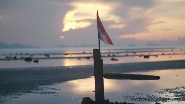 Thailand flag blow in the wind on an island beach at sunset. 