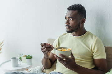 Fototapeta na wymiar bearded african american man holding bowl with corn flakes