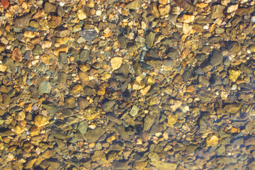 Close-up and top view of shiny transparent yellow sand and stones on the beach with clear water. clear sea, the river reveals the beauty of a natural resting place in the summer under the sun. Has a