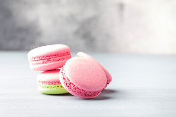 Pink yellow macaroons cakes on gray blue table background, place for text, trendy minimalism style, selective focus
