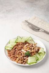 Boiled beef meat, buckwheat and cucumber in a plate on the table. Diet nutrition