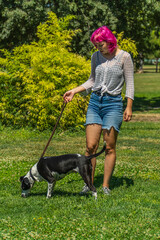 Naklejka na ściany i meble Mujer de pelo rosa paseando a su perro por el césped, perro blanco con manchas negras con su dueño en el parque, perro atado con correa en un paseo por el campo, adiestrando a un perro 