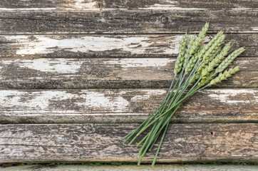 a bouquet of wheat ears lies on old wooden boards