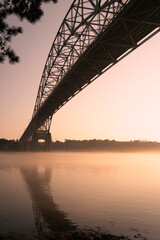 Pink Sunrise under the Bourne Bridge in the foggy summer morning on Cape Cod.