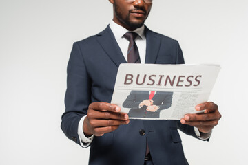 cropped view of african american man in suit reading business newspaper isolated on grey