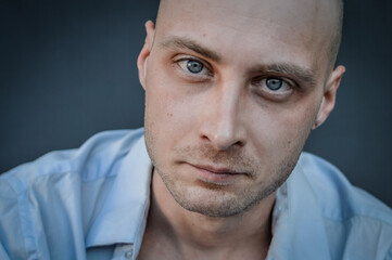 portrait of a young bald man with a grumpy look staring in front of him