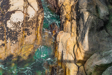 Green and blue water flowing through canyon with bubbles visible, rocks, and texturing on the rocks