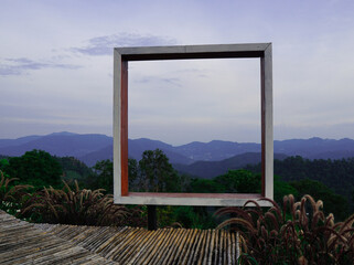 Take a photo with a square wooden frame and see the view. The old bamboo walkway is in the countryside with no terraces to prevent accidents on the background of forests and mountains