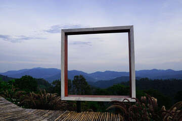 A photo spot with a rectangular wooden frame and a view The old bamboo walkway is in the countryside with no terraces to prevent accidents in the background of forests and mountains