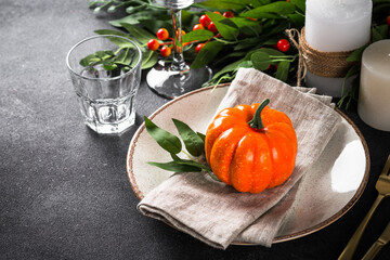 Autumn table setting with plate, pumpkin and candles. Thanksgiving food festive dinner concept.