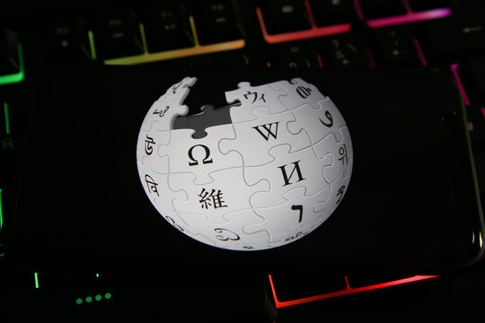 Viersen, Germany - June 9. 2021: Closeup of mobile phone with logo lettering of wikipedia on computer keyboard (focus on center of globe symbol)