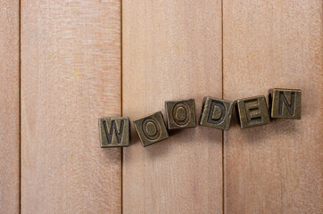 Metallic blocks forming a word "WOODEN" on plank surface