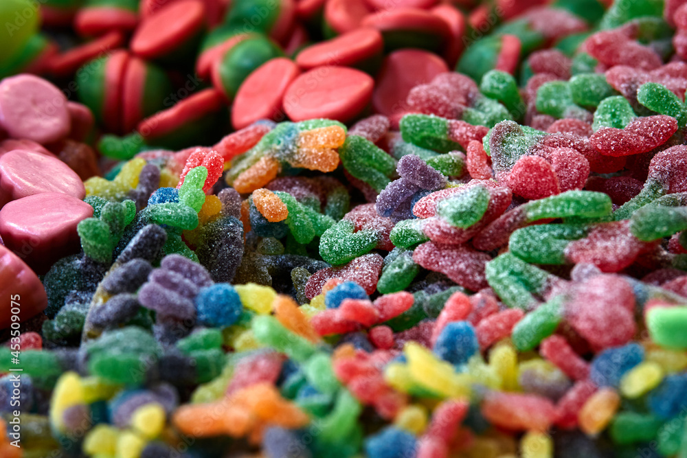 Poster a background of colorful gummy candies with different shapes and forms. selective focus.