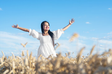 Portrait of happy young woman in a white dress, on a wheat field. Lifestyle and happiness concept. Woman with open arms . High quality photo