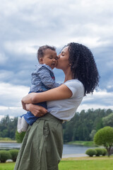 Young beautiful dark-skinned mother kisses her baby 