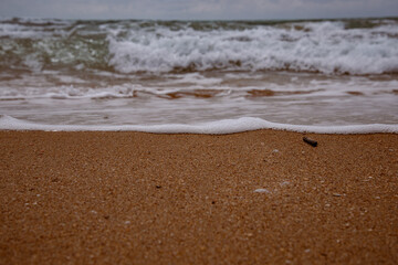 Sea waves beating against the sandy shore. Stormy ocean landscape. Vacation and travel.