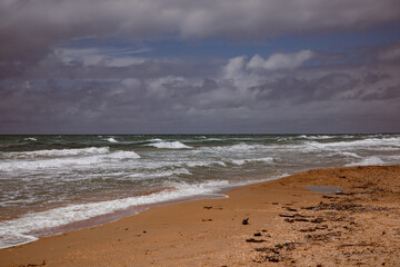 Sea waves beating against the sandy shore. Stormy ocean landscape. Vacation and travel.