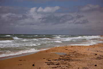 Sea waves beating against the sandy shore. Stormy ocean landscape. Vacation and travel.