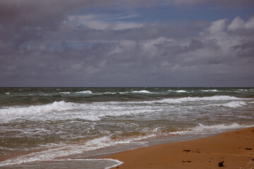 Sea waves beating against the sandy shore. Stormy ocean landscape. Vacation and travel.