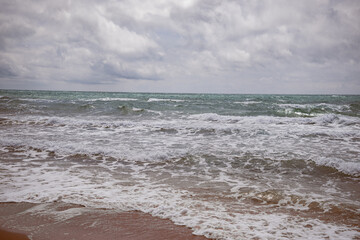 Sea waves beating against the sandy shore. Stormy ocean landscape. Vacation and travel.