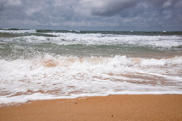 Fototapeta premium Sea waves beating against the sandy shore. Stormy ocean landscape. Vacation and travel.