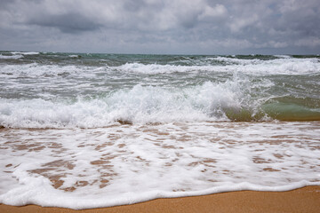 Sea waves beating against the sandy shore. Stormy ocean landscape. Vacation and travel.