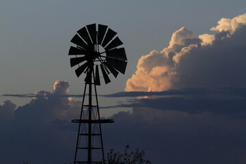 A Windmill with Cumulonimbus clouds at Sunset north of Hutchinson Kansas USA out in the country.