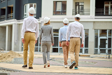 Elegant construction manager and her colleagues inspecting the building area