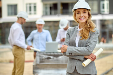 Joyous determined female construction manager in a hardhat standing outdoors