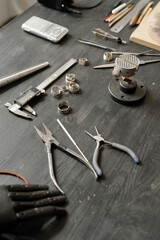 Fototapeta premium Close-up of jewelers tools including pliers and measuring tools placed on wooden table with ring blanks