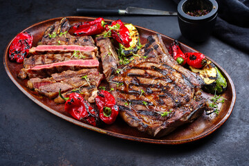 Two barbecue dry aged wagyu cote de boeuf beef steaks with zucchini and chili served as close-up on...