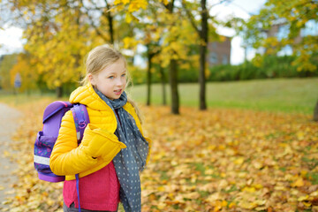 Cute young girl with a backpack heading to school on autumn morning