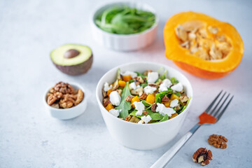 Roasted pumpkin avocado arugula goat cheese salad in a plate