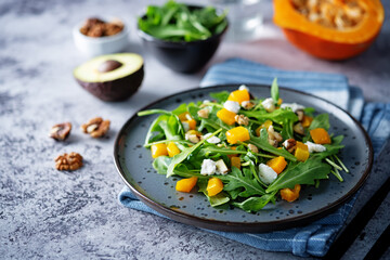 Roasted pumpkin avocado arugula goat cheese salad in a plate